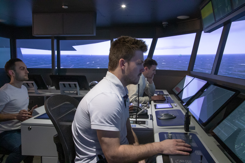 Three delegates navigating on ships bridge simulator