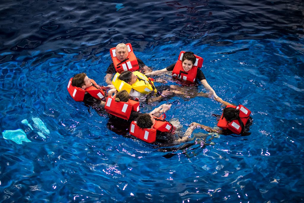 Maritime Skills Academy swimming pool with 6 delegates surrounding a trainer during a demonstration