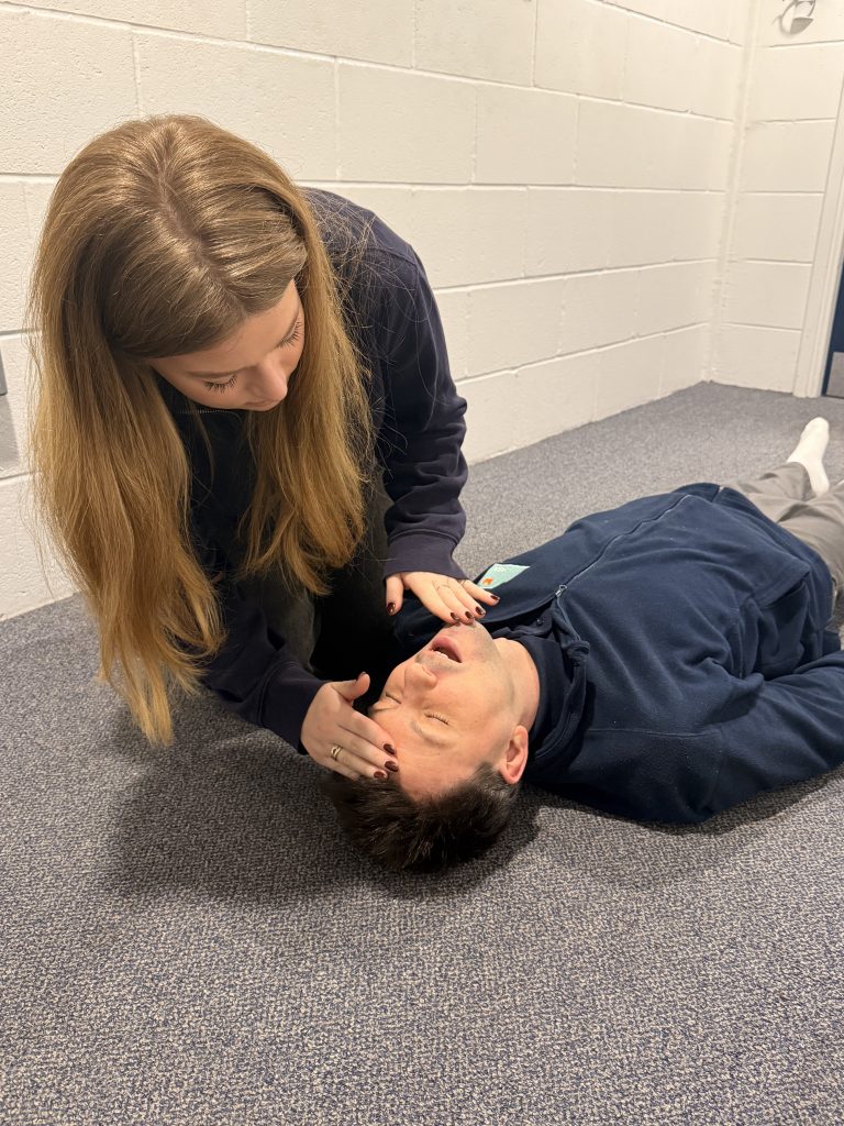 Someone checking a patient's airways in the third step of a primary survey