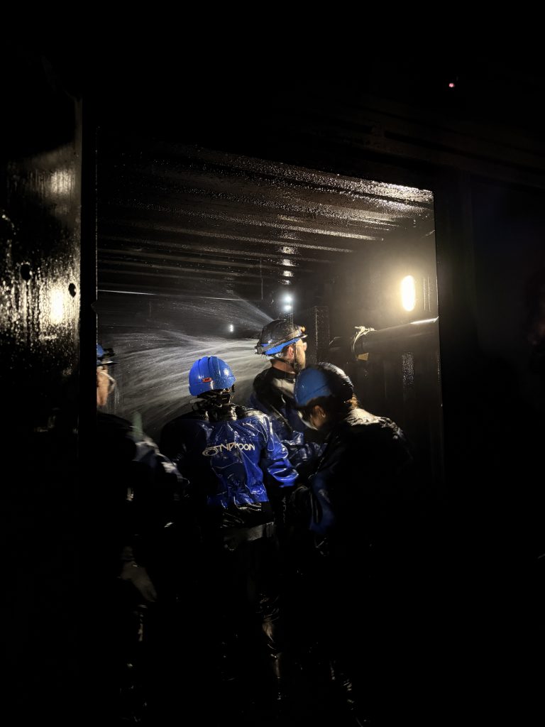 Maritime Damage Control Training at the Maritime Skills Academy in Kent. There are four crew members assessing a burst pipe with water spraying behind them. 