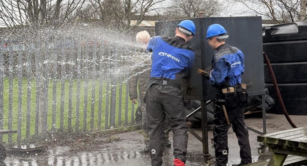 Two damage control training delegates practicing hull breach response outside