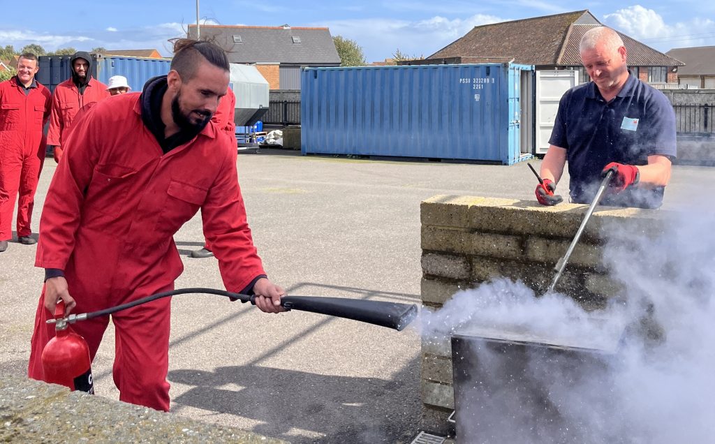 Delegate using fire extinguisher during their marine course